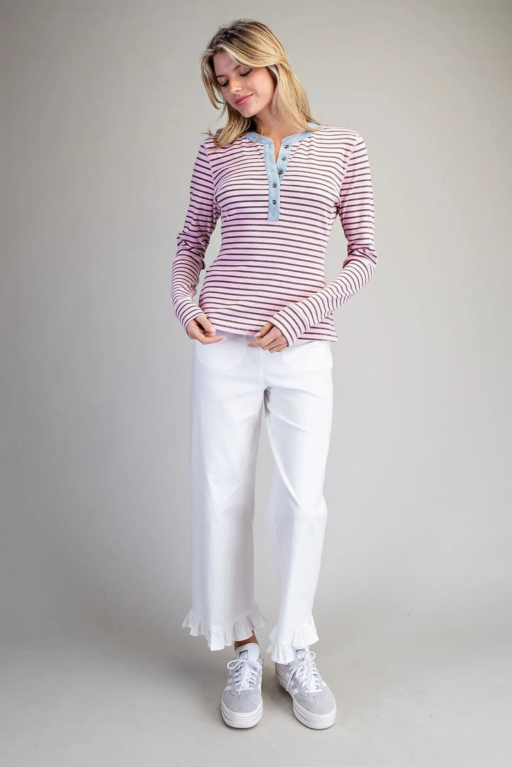 Woman wearing a striped shirt and white pants on a plain background