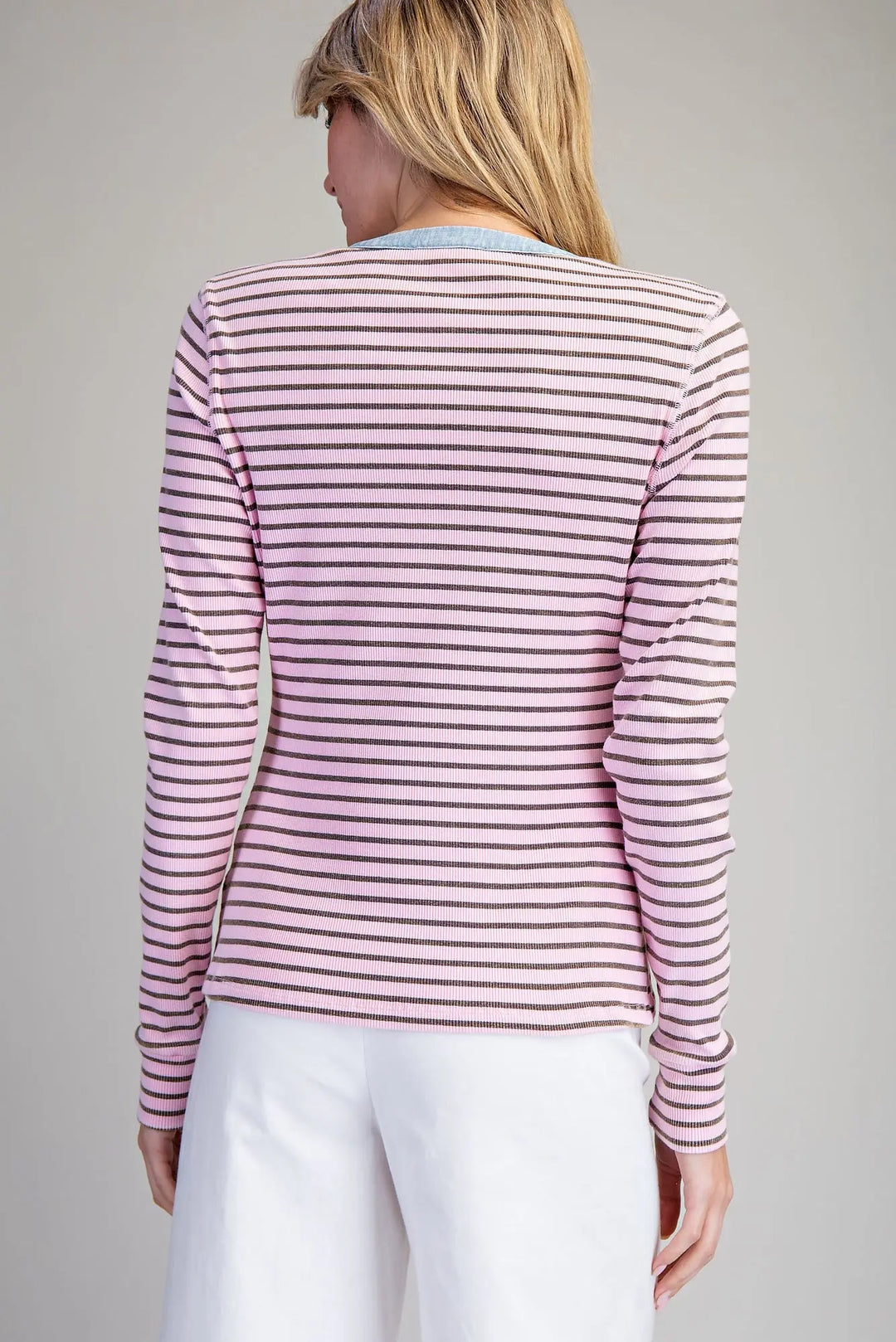Woman wearing a striped long-sleeve shirt and white pants on a gray background