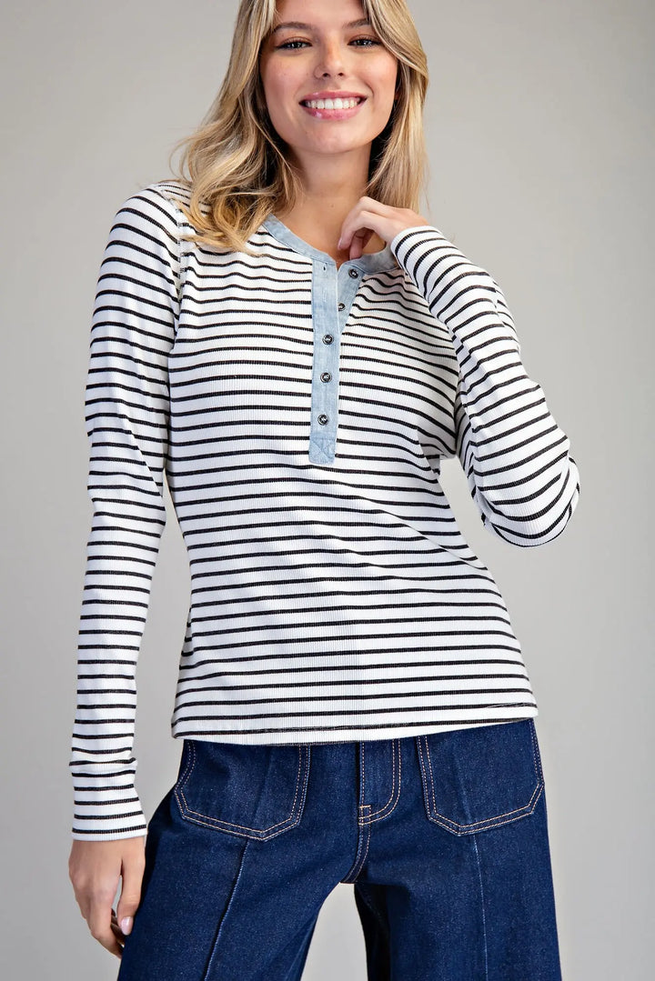 Woman wearing a striped long-sleeve shirt and blue jeans on a gray background