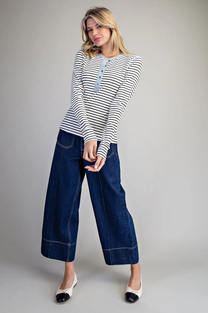 Woman wearing a striped shirt and wide-leg jeans on a gray background