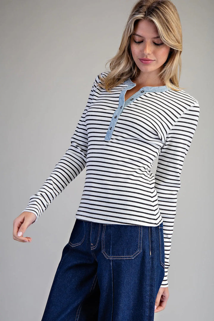Woman wearing a striped long-sleeve shirt and jeans on a gray background