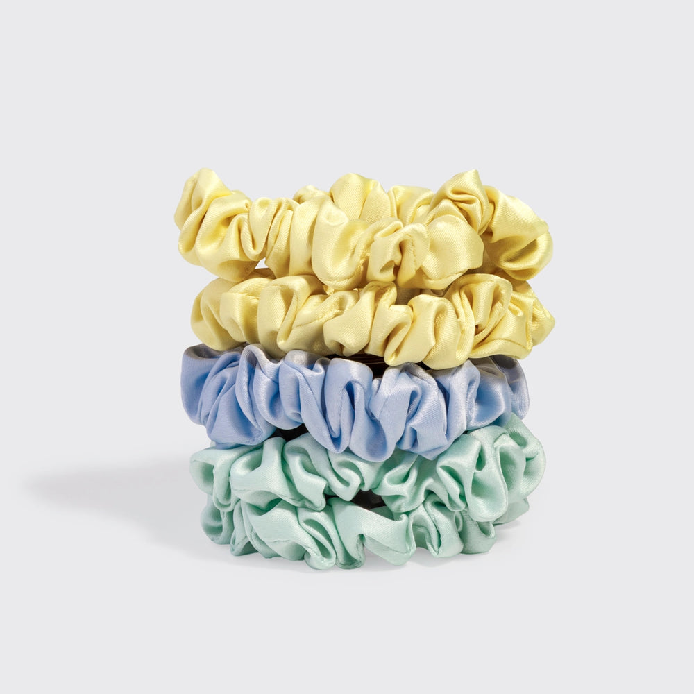 Three scrunchies in yellow, blue, and green on a light gray background