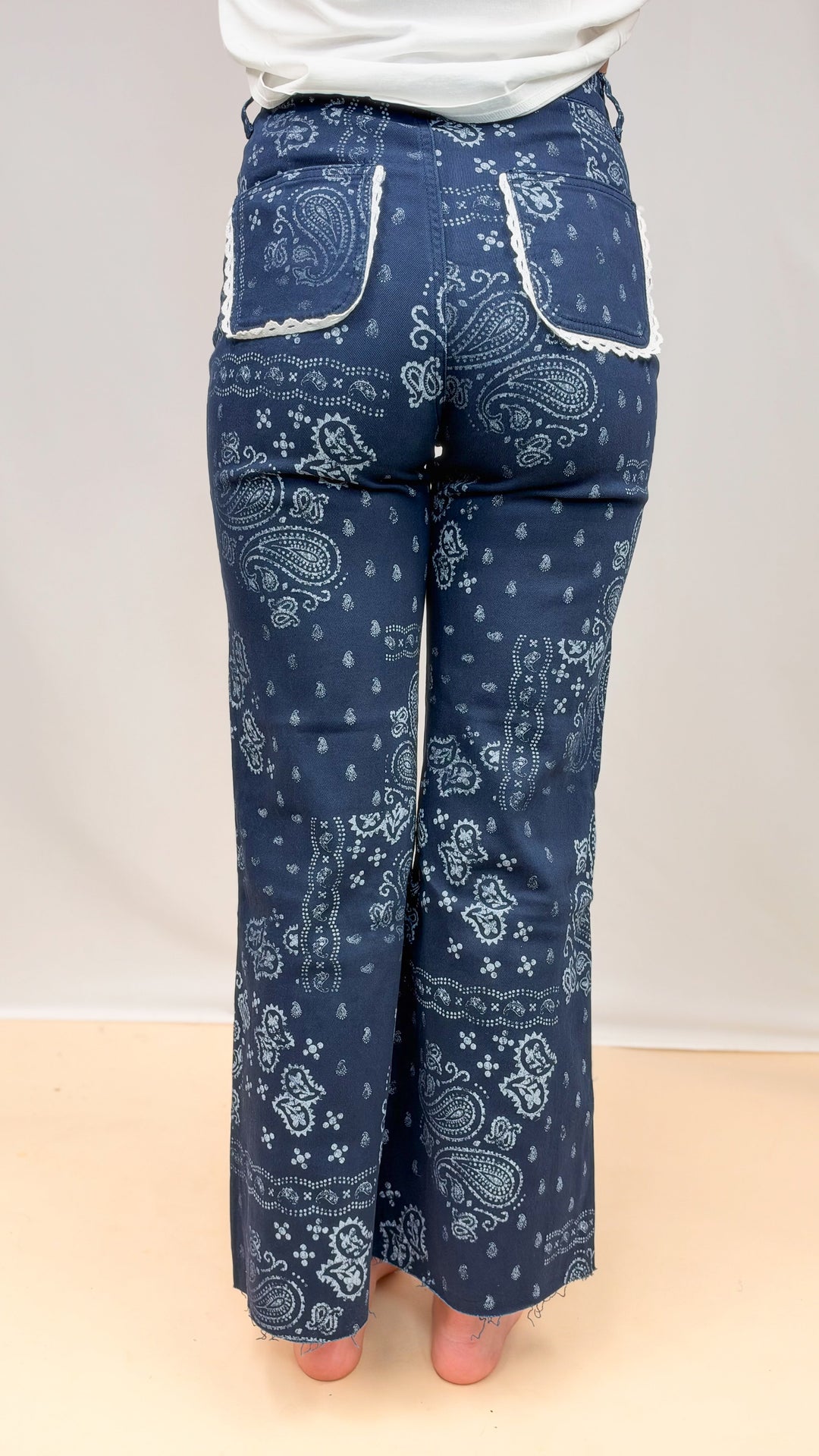 Woman shown from back wearing blue bandana print pants on plain background
