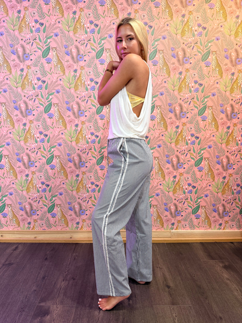 person wearing stripe pants and white top on floral background