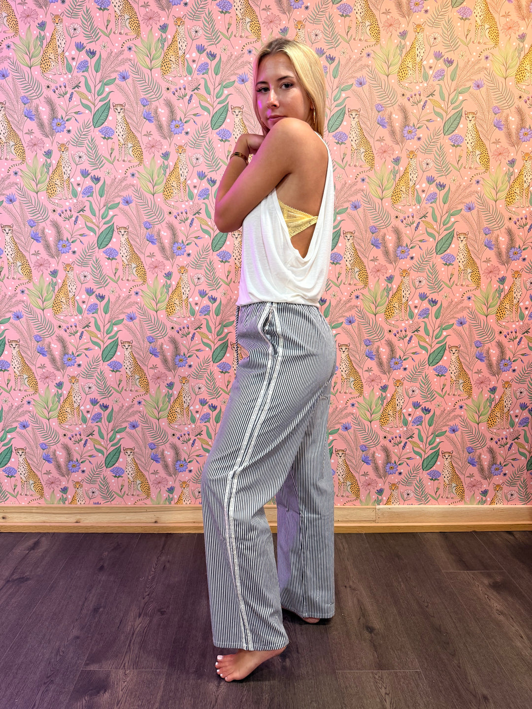 person wearing stripe pants and white top on floral background