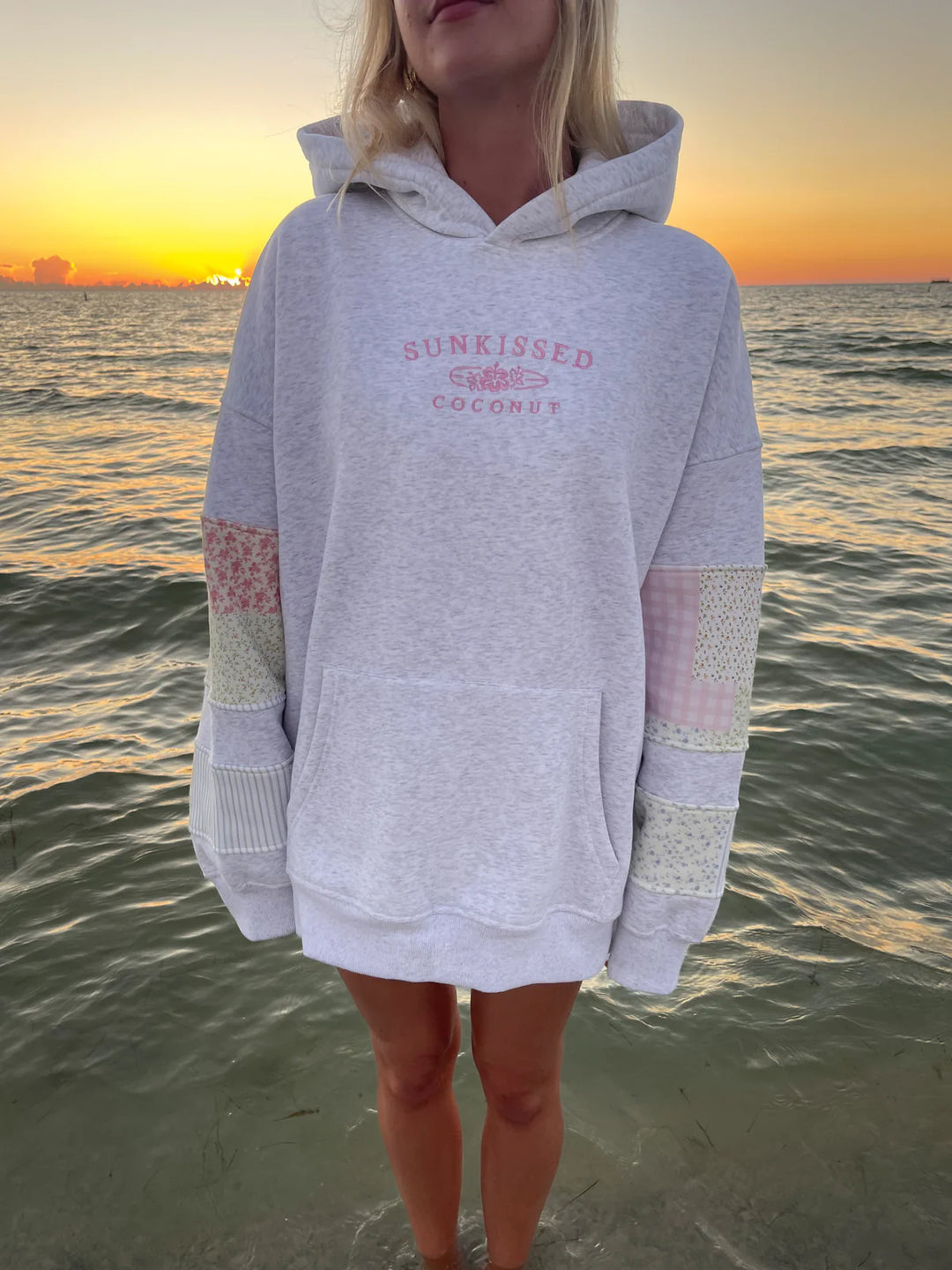 Woman wearing grey sweatshirt with embroidery and patchwork standing in the water