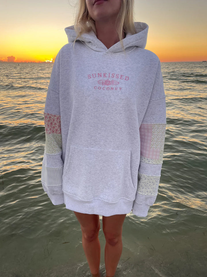 Woman wearing grey sweatshirt with embroidery and patchwork standing in the water