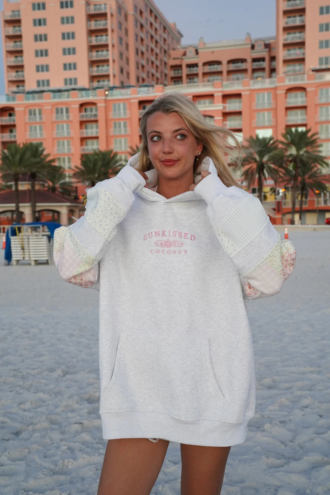 Girl wearing grey sweatshirt with embroidery and patchwork detail on the beach
