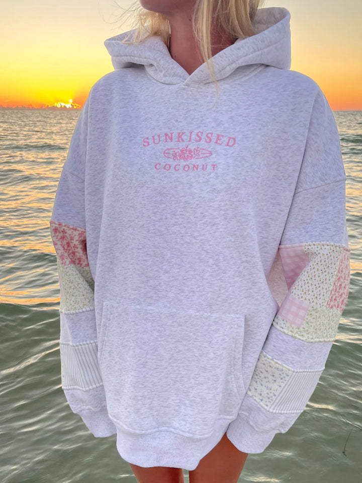 Girl wearing grey sweatshirt with embroidery and patchwork detail on elbows on the water