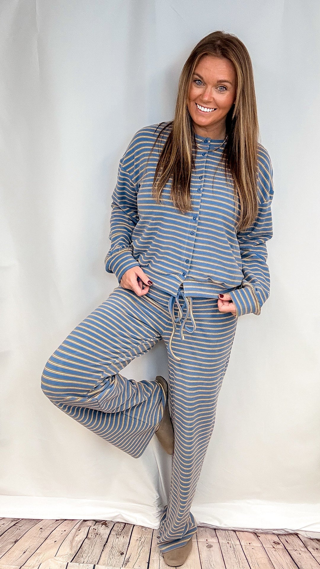 Woman wearing matching blue and yellow stripe set on plain background