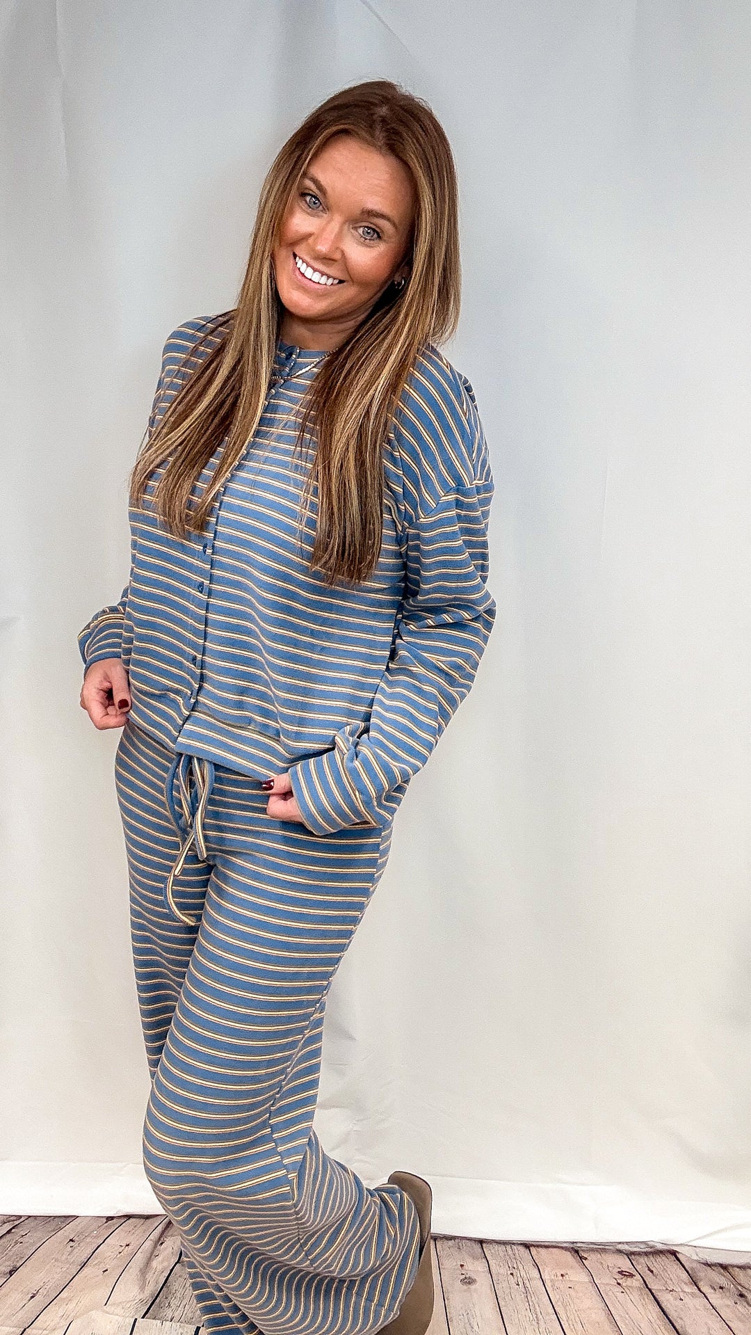 Woman wearing matching blue and yellow stripe set on plain background