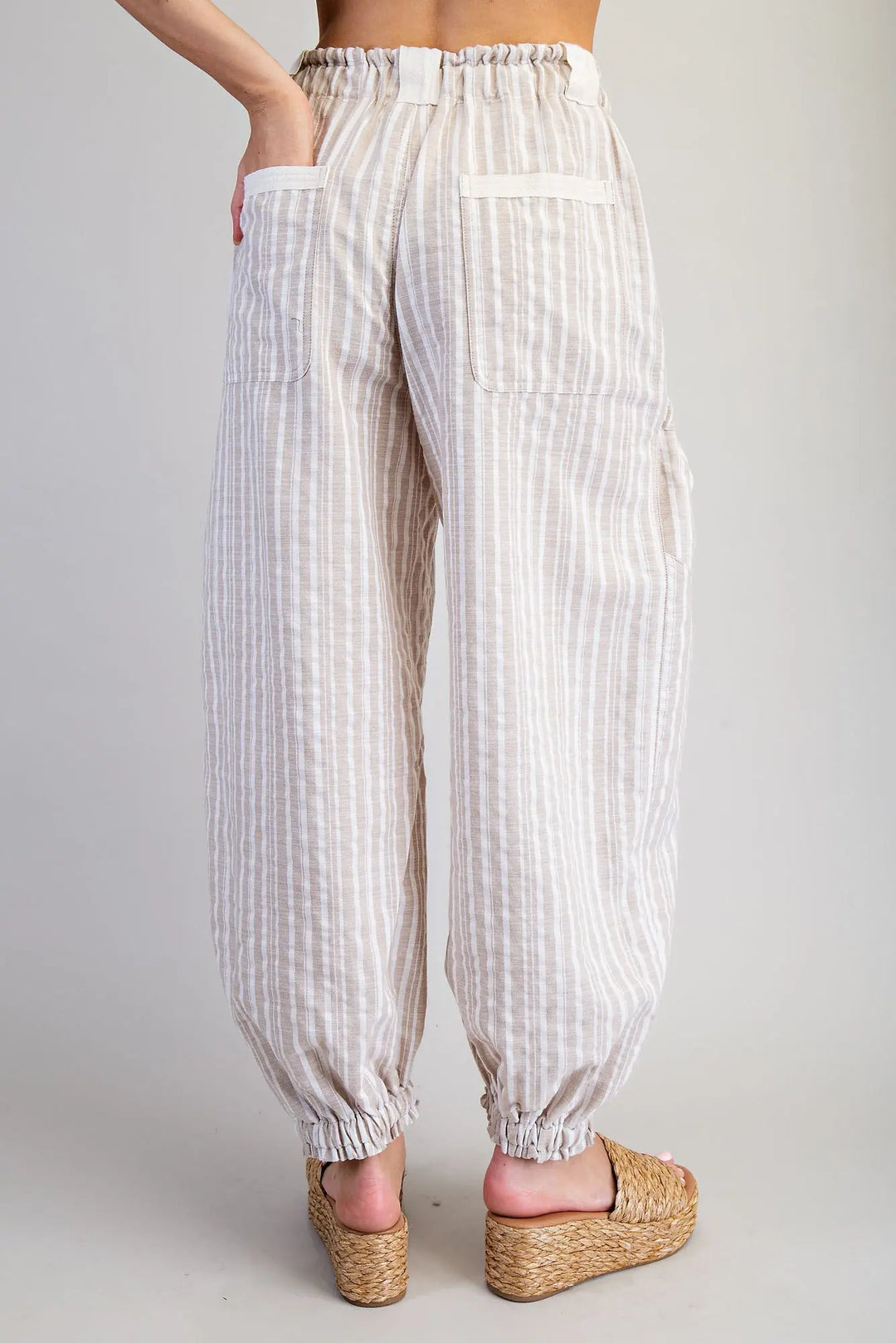 White striped pants worn by a person on a plain background