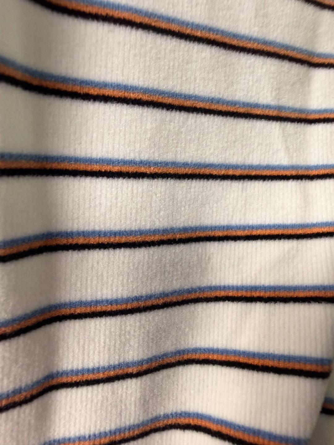 Close-up of striped fabric with blue, brown, and black lines on a white background