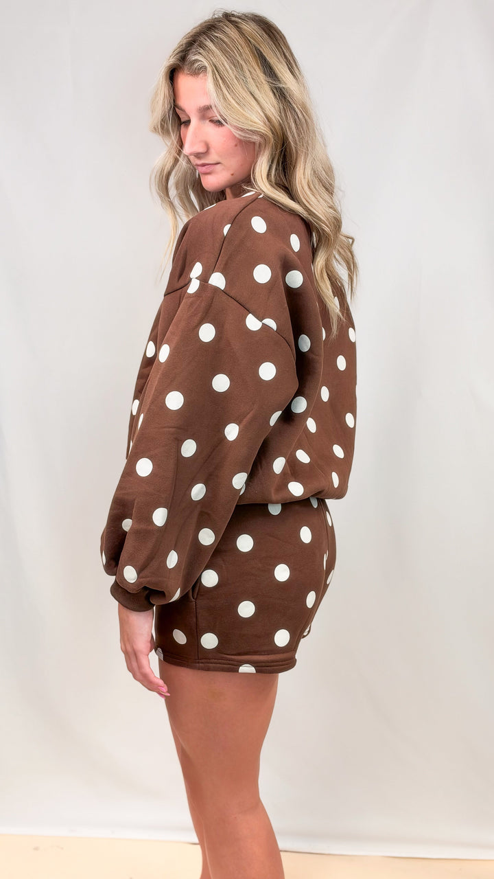 Woman shown from side view wearing matching brown set with cream polka dots on plain background