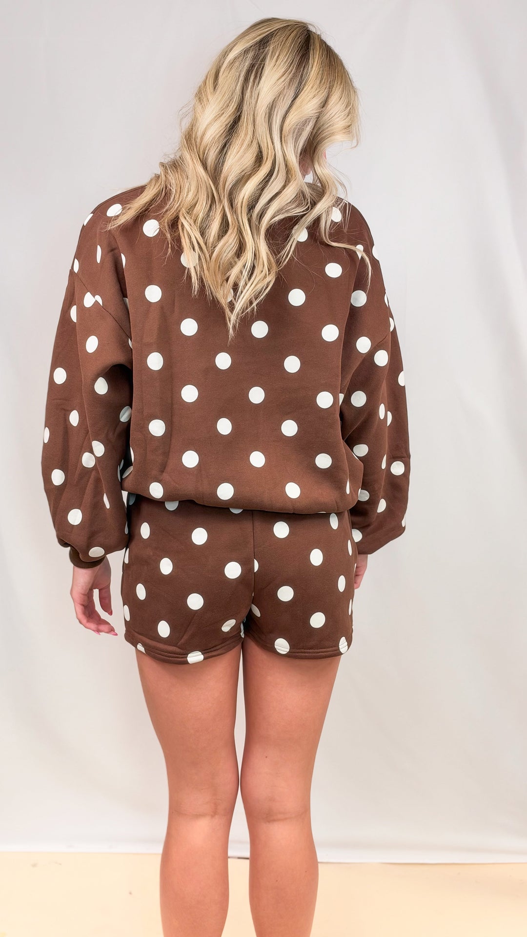 Woman shown from back view wearing matching brown set with cream polka dots on plain background