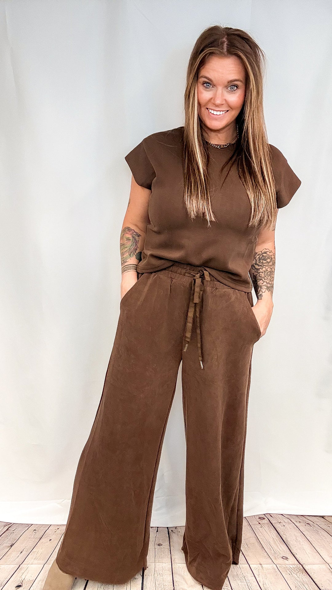 Woman wearing matching brown set on plain white background