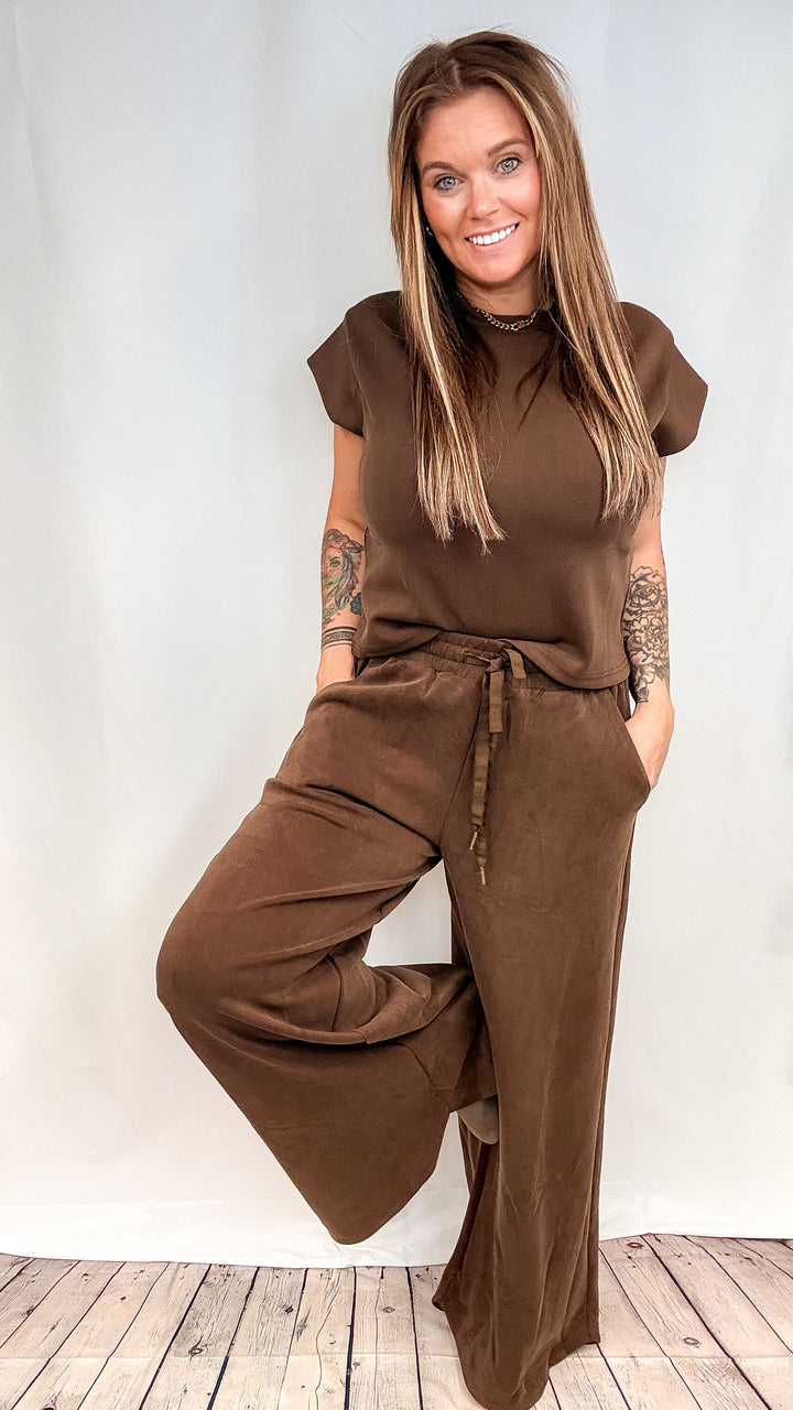Woman wearing matching brown lounge set on white background