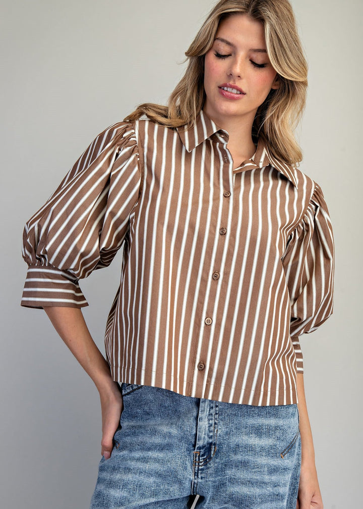 Woman wearing brown and white stripe puff sleeve blouse and denim jeans on white background