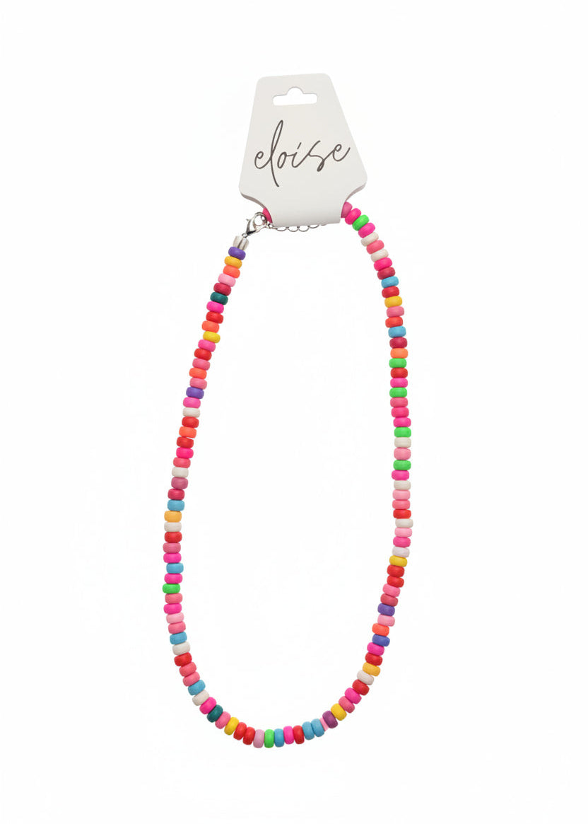 A colorful beaded necklace with small round beads in pink, blue, yellow, green, orange, and white, displayed on a white card labeled &