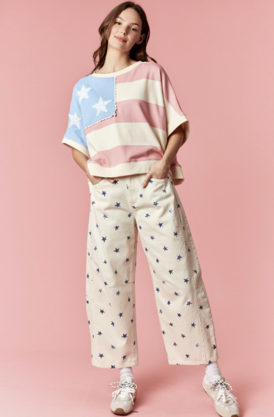 Woman wearing a colorful top and patterned pants on a pink background