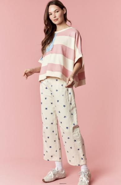 Woman wearing a striped poncho and patterned pants on a pink background