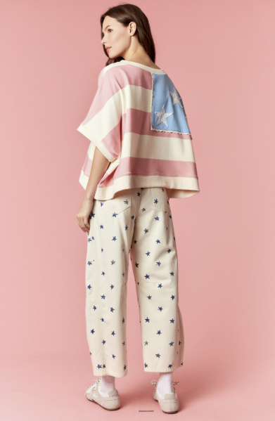 Woman wearing a colorful top and star-patterned pants on a pink background