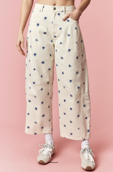 Person wearing cream pants with blue star pattern on a pink background