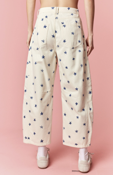 Cream-colored pants with blue star pattern worn by a person on a pink background