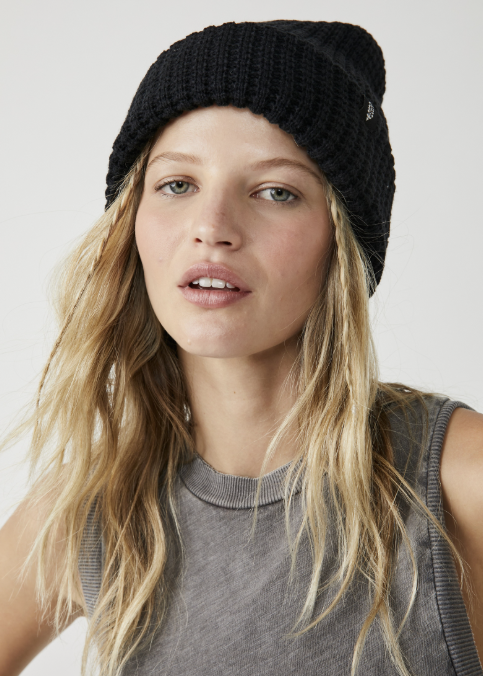Woman wearing black beanie with gray tank on plain background