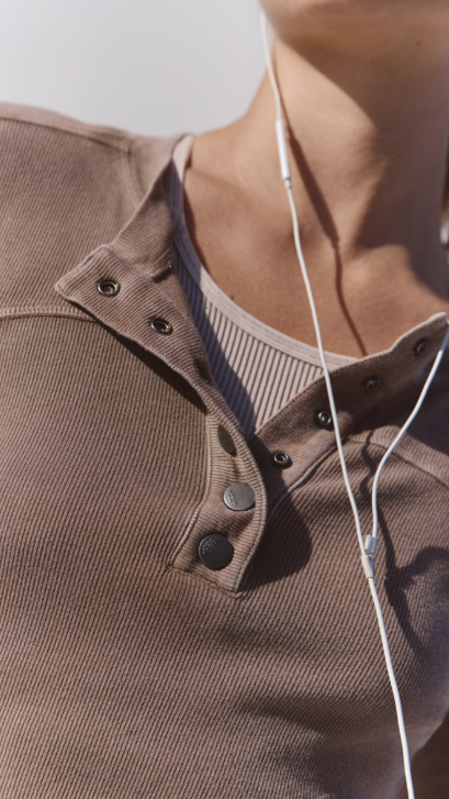 Close up of woman wearing brown henley top on white background