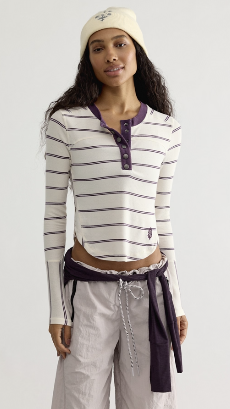 Woman wearing white and purple stripe long sleeve top and beige pants on white background