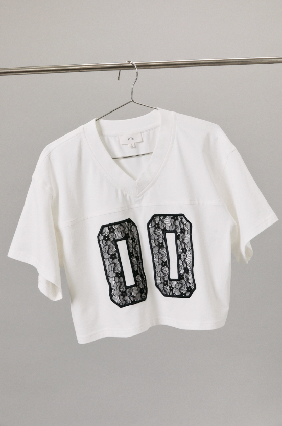 White crop top with black lace details on a gray background