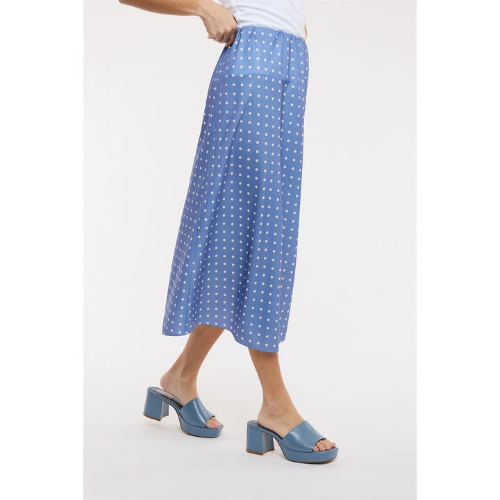 Woman wearing blue polka dot midi satin skirt on plain background