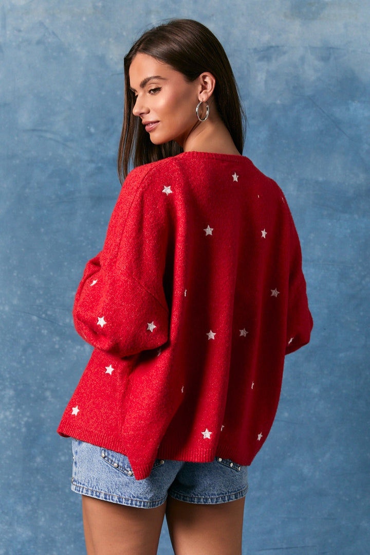 Woman wearing red cardigan with white stripes and denim shorts on blue background