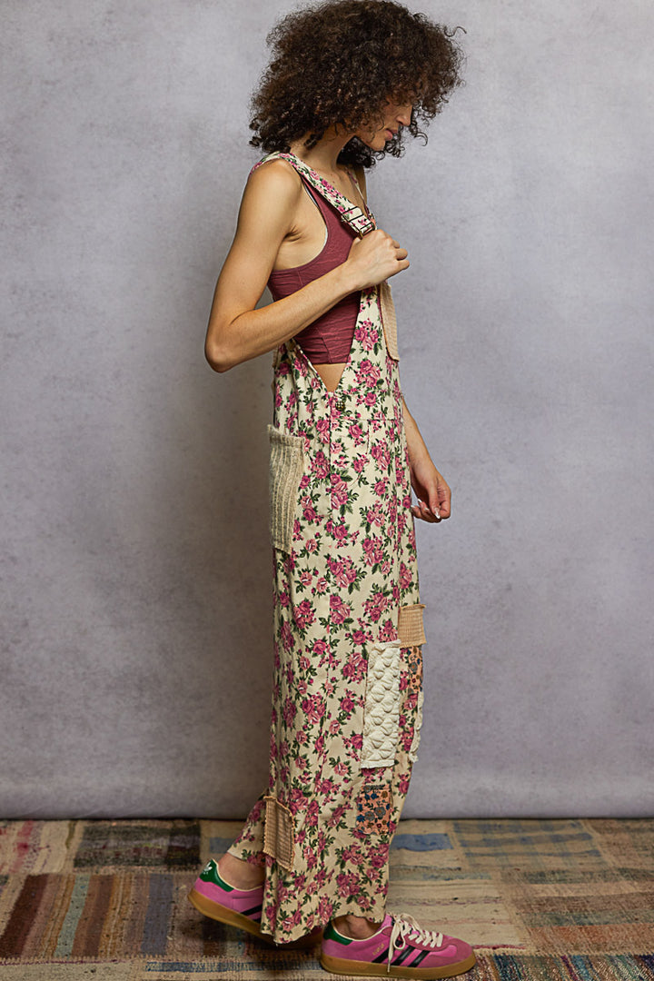 Woman wearing a floral dress and maroon top against a gray wall.