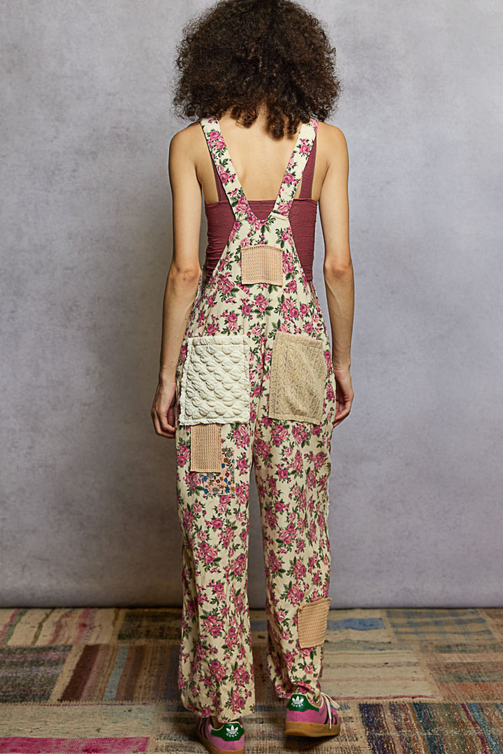 Person wearing a floral overalls with a textured wall and rug in the background