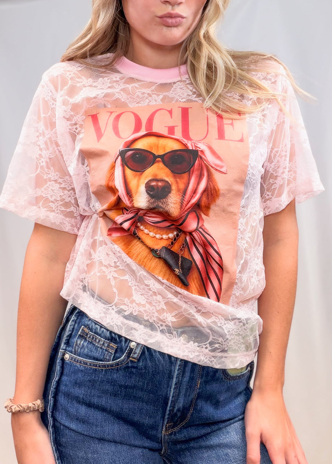 Woman wearing pink lace tee with golden retriever graphic on front with plain background