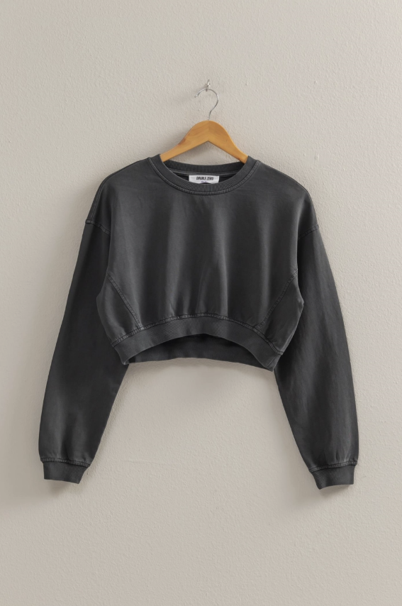 Black sweatshirt on a wooden hanger against a beige wall