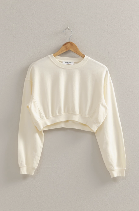 Cream pullover on wooden hanger on plain background