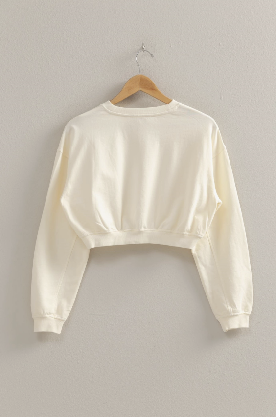 Cream pullover on wooden hanger on plain background
