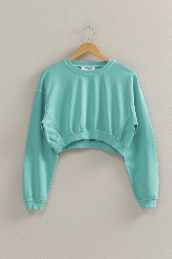 Turquoise pullover on wooden hanger on plain background