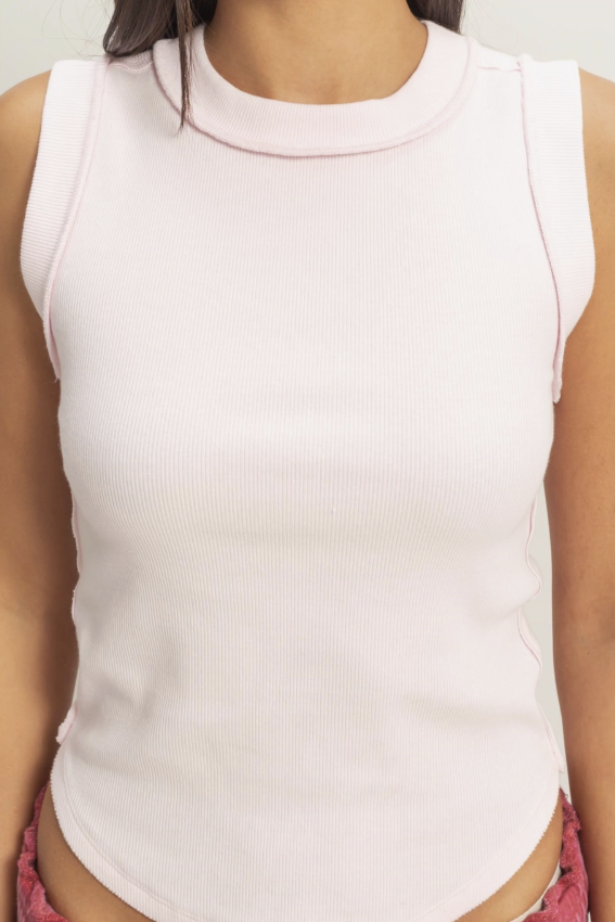 Person wearing a light pink sleeveless top with a blurred background