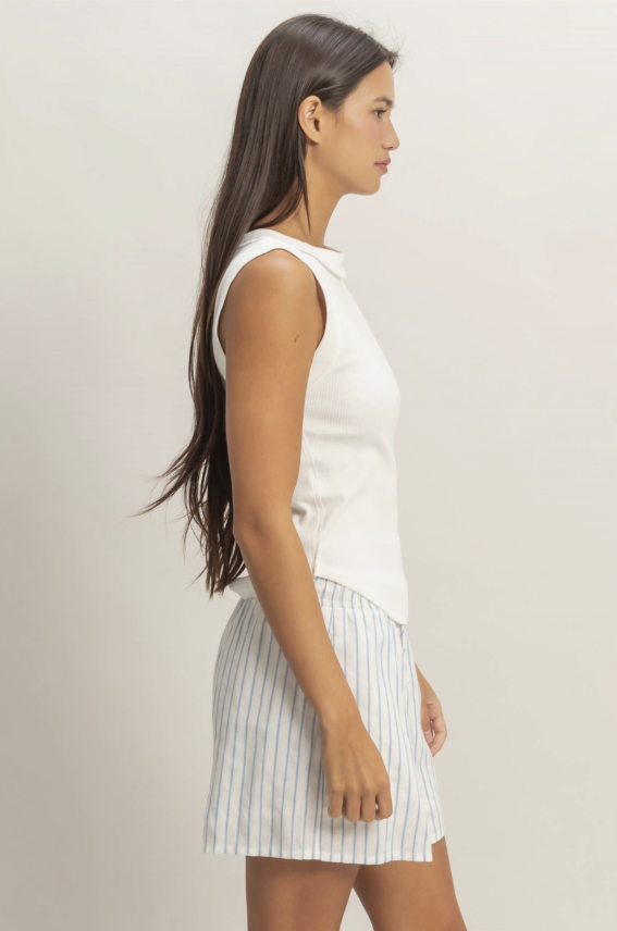 Woman wearing a white sleeveless top and striped skirt against a plain background
