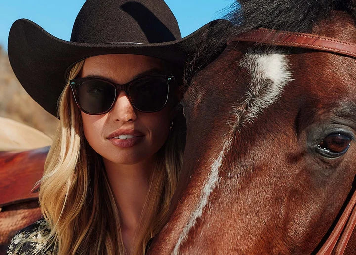 Woman wearing sunglasses next to a horse face