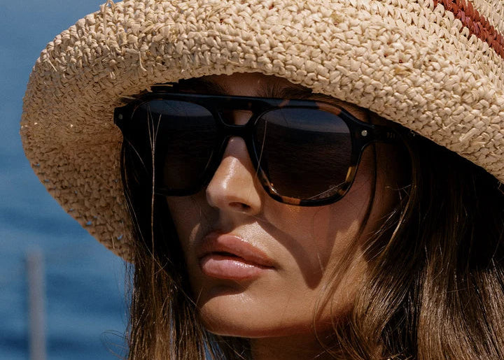 Woman wearing tortoise sunglasses with hat outdoors