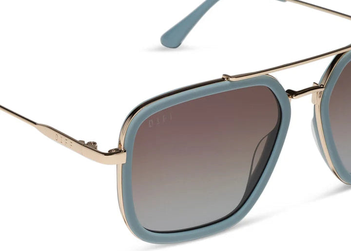 Close up of blue sunglasses with gold frame on white background