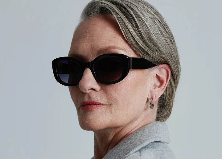 Woman wearing black sunglasses on plain background