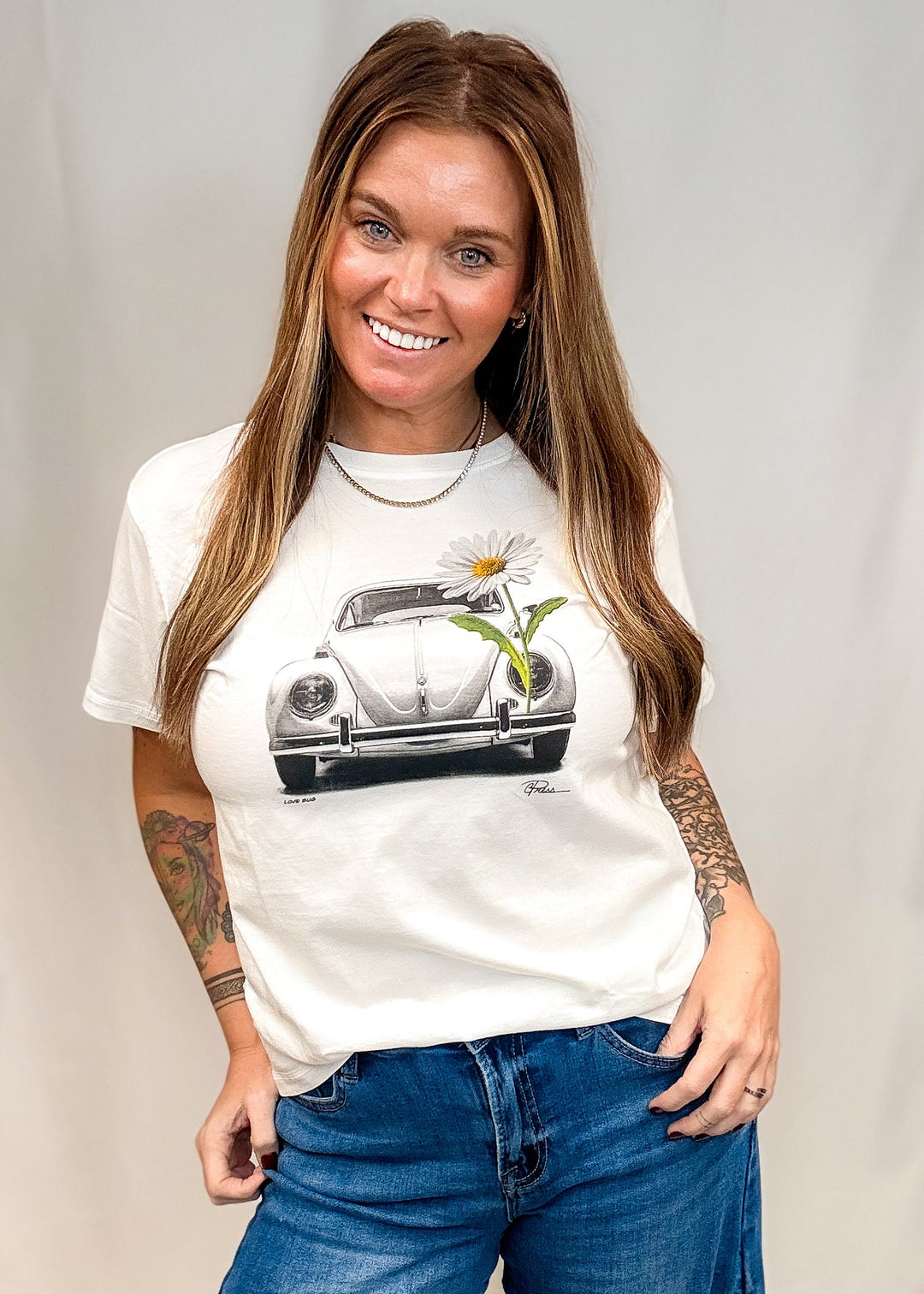 Woman wearing white graphic tee with vintage graphic Volkswagen beetle and daisy on white background