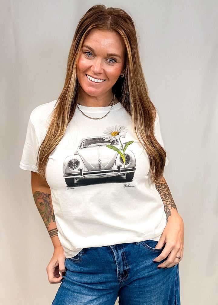 Woman wearing white graphic tee with vintage graphic Volkswagen beetle and daisy on white background