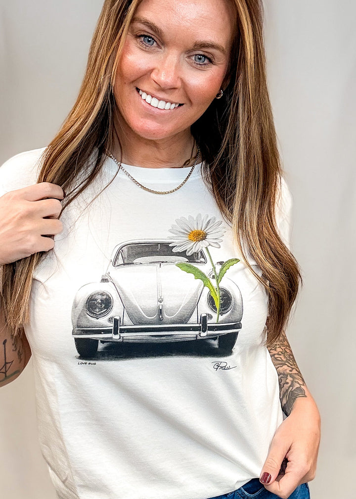 Woman wearing white graphic tee with vintage Volkswagen beetle and daisy on white background